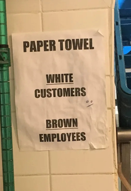 Un cartel en la pared dice: "Toalla de papel: Blanco - Clientes, Marrón - Empleados," sugiriendo un acceso independiente